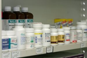 A person examines a prescription medication bottle and label closely on a kitchen counter.