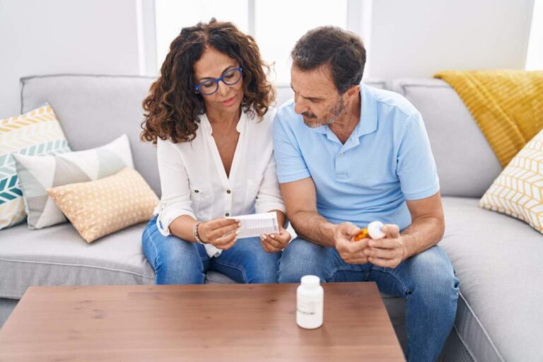 A hand places a medicine bottle on a high shelf in a home closet away from sunlight and heat vents.