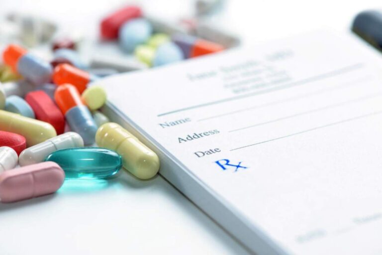 Assorted colorful pills and capsules arranged on a plain white surface.