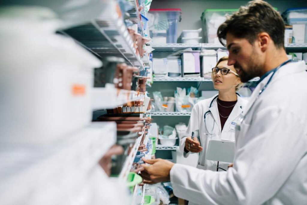 A pharmacist shows a prescription bottle and explains directions to a patient across the counter.